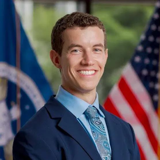 Zachary Harris smiling and standing in front of an American flag.
